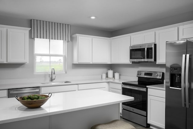 kitchen with stainless steel appliances, light countertops, white cabinets, and a sink