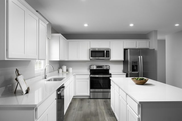 kitchen featuring appliances with stainless steel finishes, wood finished floors, light countertops, white cabinetry, and a sink