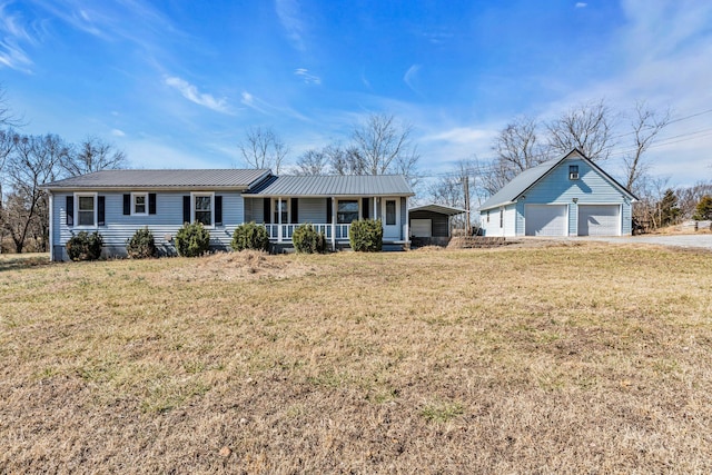 ranch-style house featuring metal roof, a porch, a detached garage, and a front yard