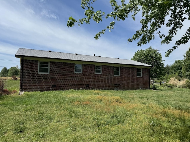 view of side of home featuring crawl space, brick siding, and metal roof