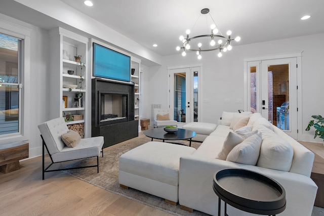 living room with built in features, french doors, a fireplace, recessed lighting, and wood finished floors