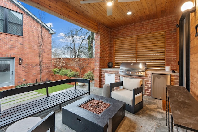 view of patio / terrace with a fire pit, exterior kitchen, grilling area, and a fenced backyard