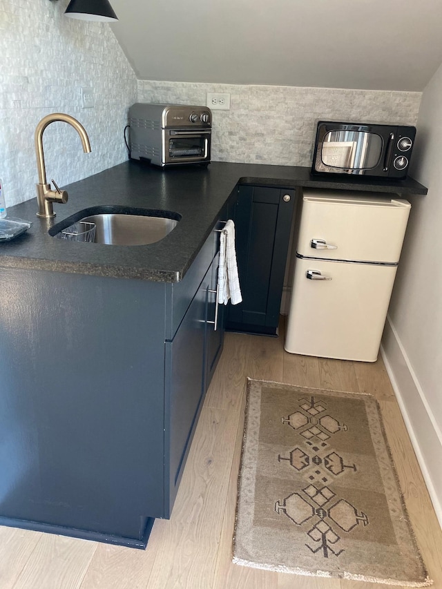 kitchen featuring dark countertops, a toaster, a sink, and light wood finished floors