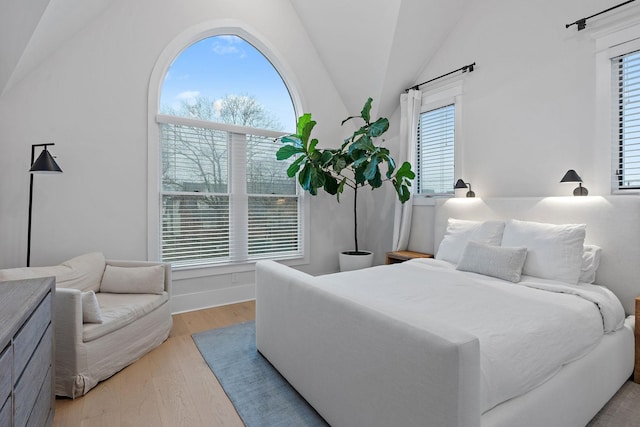 bedroom featuring light wood-style floors, lofted ceiling, and multiple windows