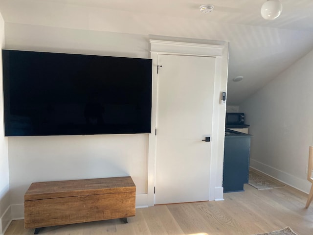 bedroom featuring vaulted ceiling, light wood-style flooring, and baseboards