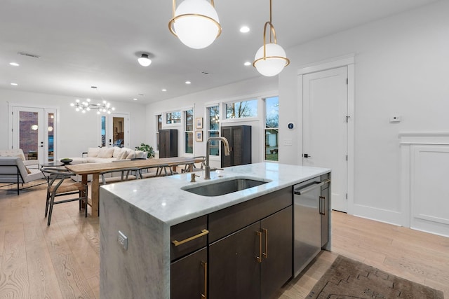 kitchen with pendant lighting, a sink, light wood finished floors, and dishwasher