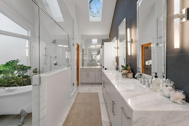 full bathroom with double vanity, a stall shower, a skylight, marble finish floor, and a sink