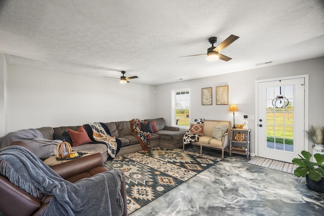 living room featuring a ceiling fan, visible vents, and a textured ceiling