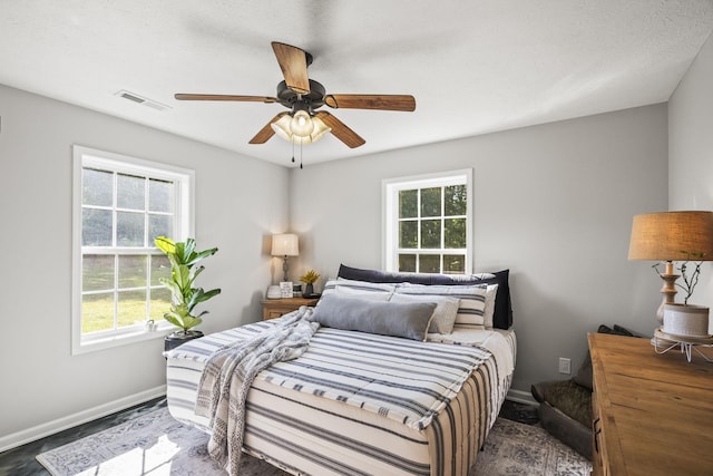 bedroom with baseboards, multiple windows, visible vents, and a ceiling fan