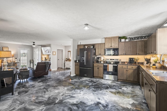 kitchen with dark countertops, open floor plan, a sink, a textured ceiling, and black appliances