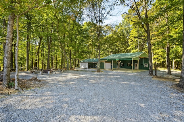 view of front of home featuring driveway, an attached garage, and metal roof