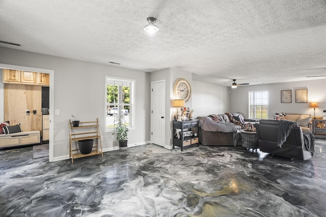 living area with a healthy amount of sunlight, baseboards, finished concrete flooring, and visible vents