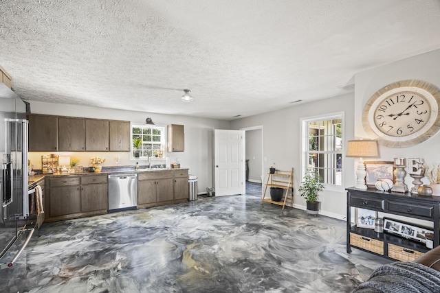 kitchen featuring dark countertops, appliances with stainless steel finishes, dark brown cabinetry, a textured ceiling, and baseboards