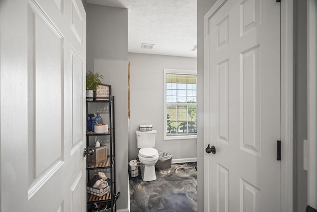 bathroom featuring a textured ceiling, visible vents, toilet, and baseboards