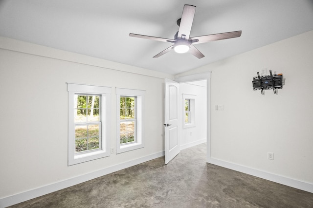 empty room featuring a ceiling fan, lofted ceiling, concrete floors, and baseboards