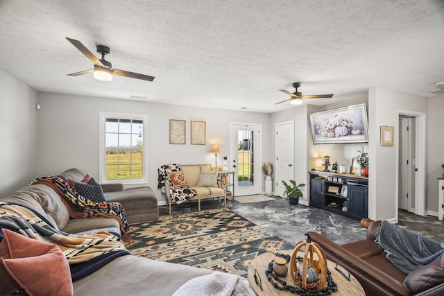 living area with visible vents, ceiling fan, a textured ceiling, and baseboards