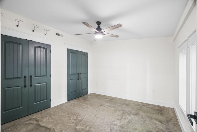 unfurnished bedroom with a ceiling fan, visible vents, concrete floors, and baseboards