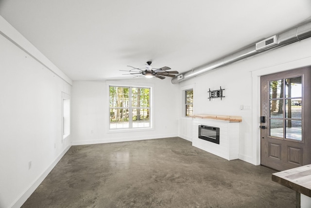 unfurnished living room featuring baseboards, a glass covered fireplace, lofted ceiling, ceiling fan, and concrete floors