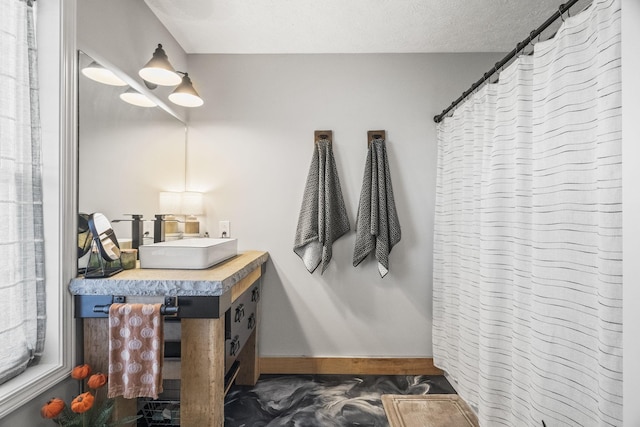 bathroom featuring curtained shower, a textured ceiling, baseboards, and vanity