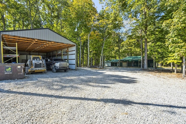 view of vehicle parking featuring driveway, a pole building, and a detached carport