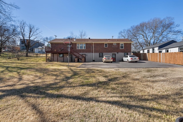 back of property with brick siding, fence, stairway, and a lawn