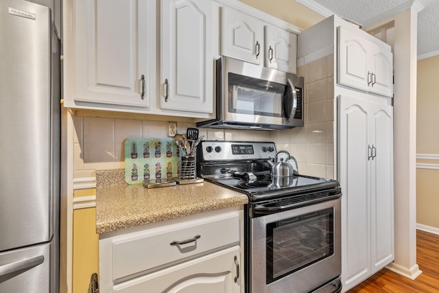 kitchen with white cabinets, tasteful backsplash, stainless steel appliances, and wood finished floors