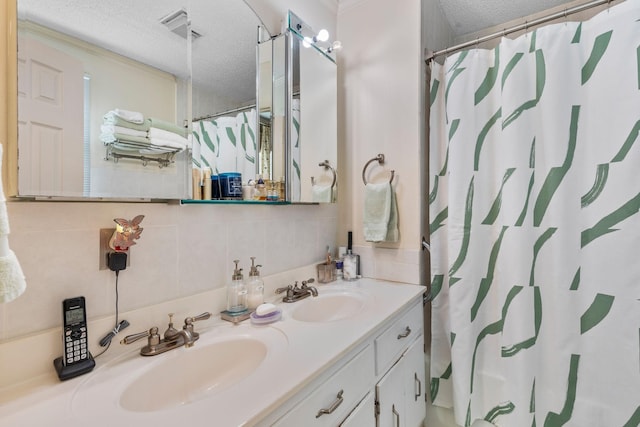 full bathroom featuring a sink, a textured ceiling, decorative backsplash, and double vanity