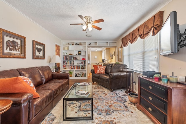 living area with a ceiling fan, crown molding, and a textured ceiling