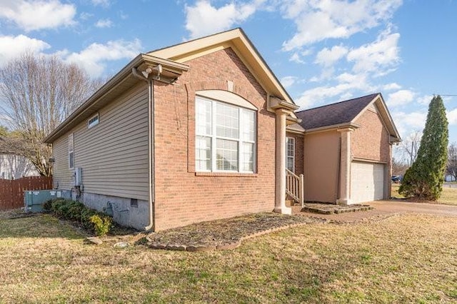 view of home's exterior featuring crawl space, driveway, brick siding, and a lawn