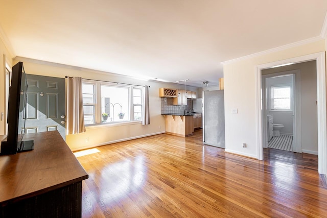 unfurnished living room featuring crown molding, baseboards, and light wood-style floors