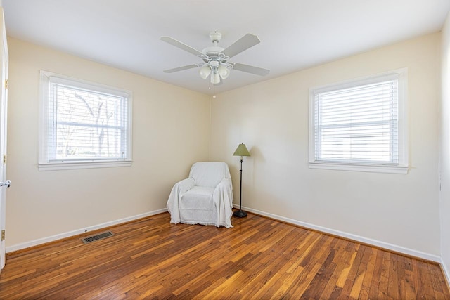 unfurnished room with ceiling fan, wood finished floors, visible vents, and baseboards