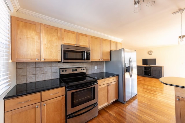 kitchen featuring dark countertops, light wood-style floors, stainless steel appliances, and crown molding