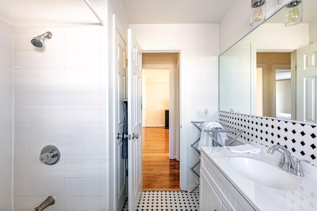 bathroom with backsplash, walk in shower, and vanity