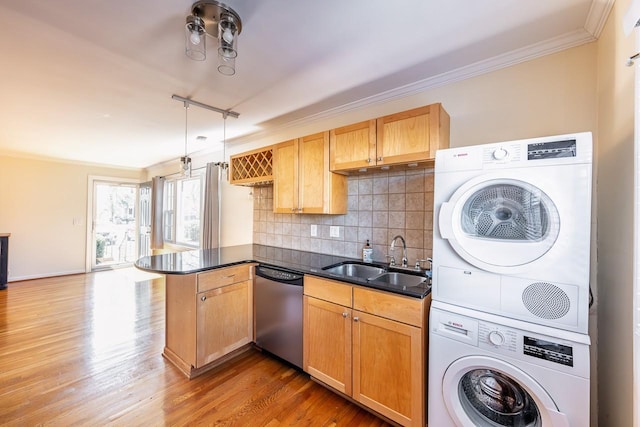 kitchen featuring stacked washer / drying machine, ornamental molding, a sink, dishwasher, and a peninsula