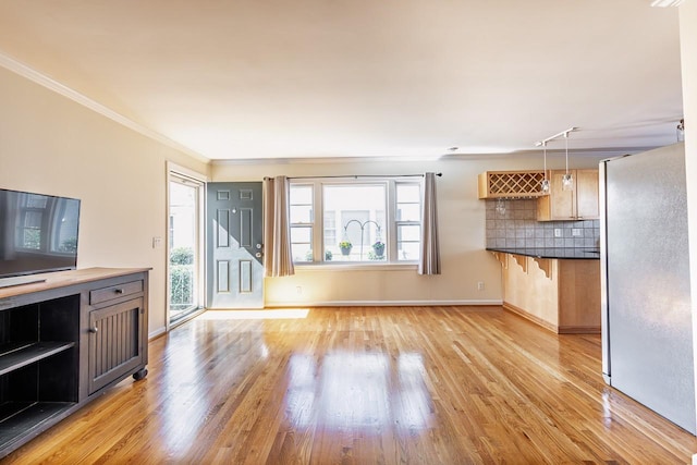 unfurnished living room with crown molding, light wood-type flooring, and plenty of natural light