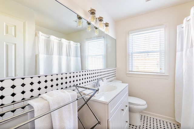 bathroom with toilet, a shower with curtain, baseboards, and vanity