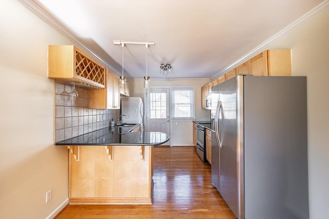 kitchen featuring stainless steel appliances, dark countertops, a peninsula, and decorative backsplash