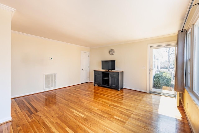 unfurnished living room with ornamental molding, light wood-type flooring, visible vents, and baseboards