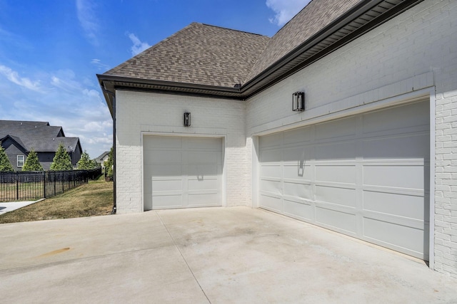 garage featuring concrete driveway and fence