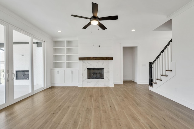 unfurnished living room featuring a fireplace, recessed lighting, stairway, light wood-style floors, and baseboards