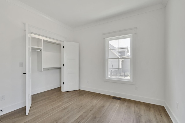 unfurnished bedroom featuring baseboards, crown molding, visible vents, and light wood-style floors