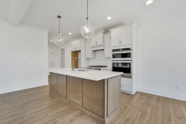 kitchen featuring double oven, a sink, backsplash, and light wood finished floors