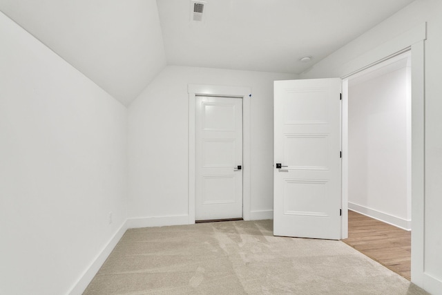 additional living space featuring baseboards, visible vents, vaulted ceiling, and carpet flooring