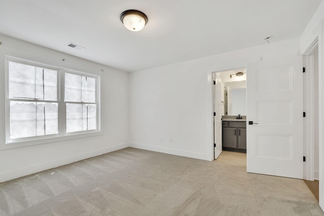 empty room featuring visible vents, baseboards, a sink, and light colored carpet