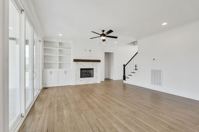 unfurnished living room with stairway, visible vents, a fireplace, and light wood-style flooring