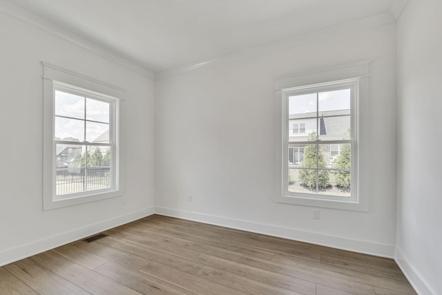 spare room featuring light wood-type flooring, plenty of natural light, visible vents, and baseboards