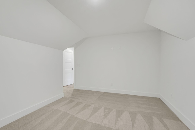 additional living space featuring lofted ceiling, light colored carpet, and baseboards