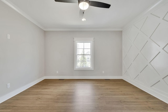 empty room featuring light wood-type flooring, a ceiling fan, baseboards, and crown molding