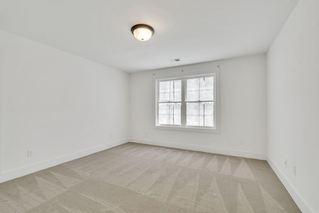 spare room featuring baseboards, visible vents, and light colored carpet