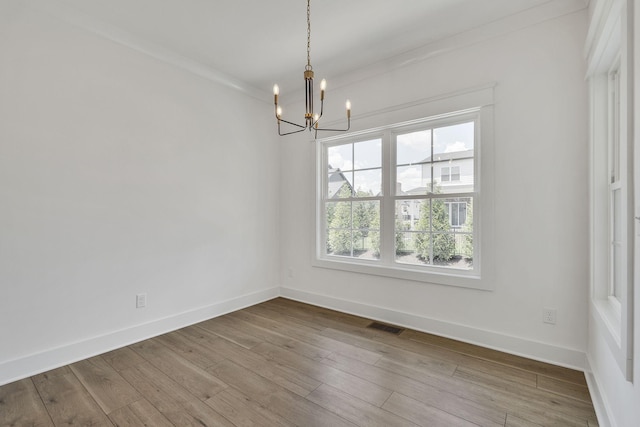 empty room with wood finished floors, visible vents, and baseboards